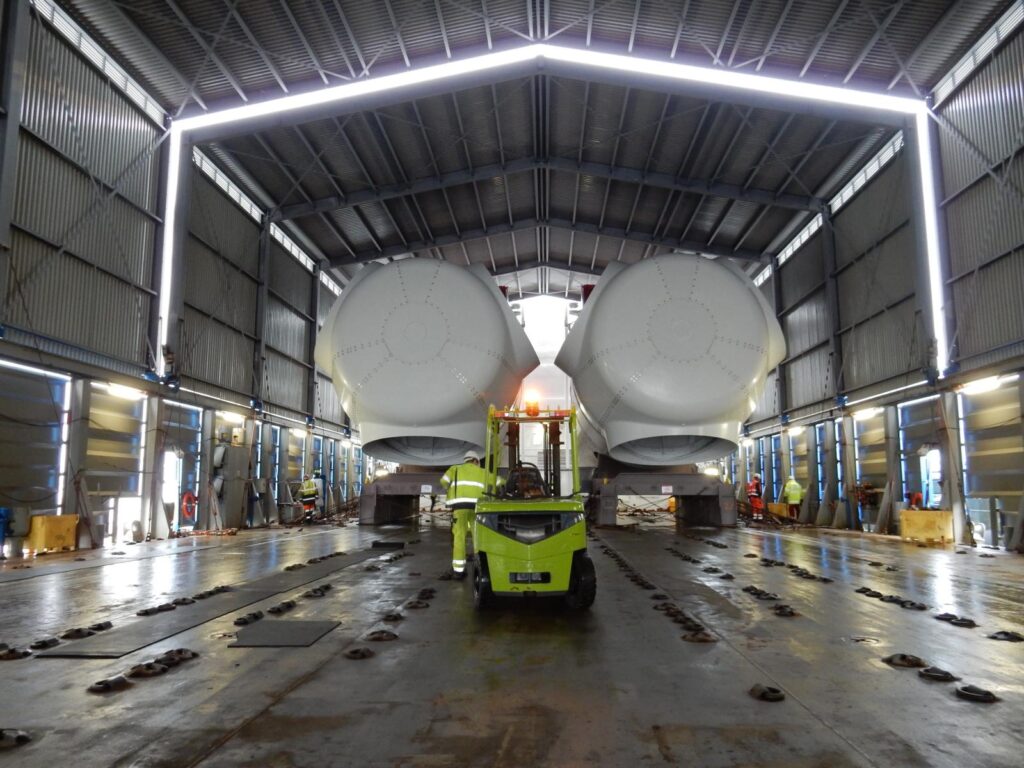 Transport von zwei Windkraft-Gondeln (Nacelles) mit Gabelstapler in einer Industriehalle – transporttechniker-de