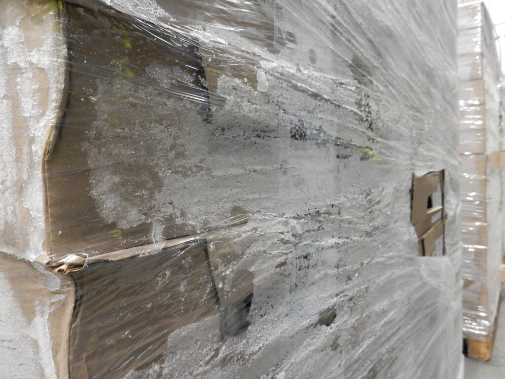 Eiskristalle zwischen Folie und Kartons auf Palette im Tiefkühllager – vereiste Verpackungen durch Kälte und Kondensation.