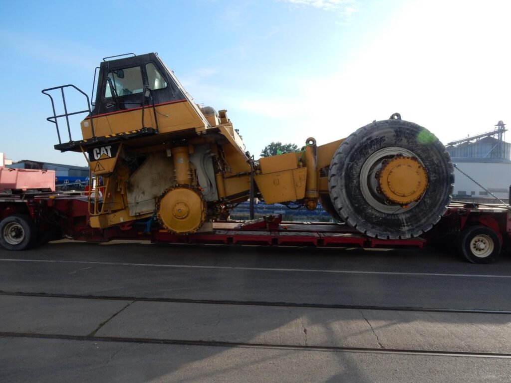 Schwerlasttransport eines gelben Caterpillar-Radladers mit großen Reifen auf Tieflader – transporttechniker-de