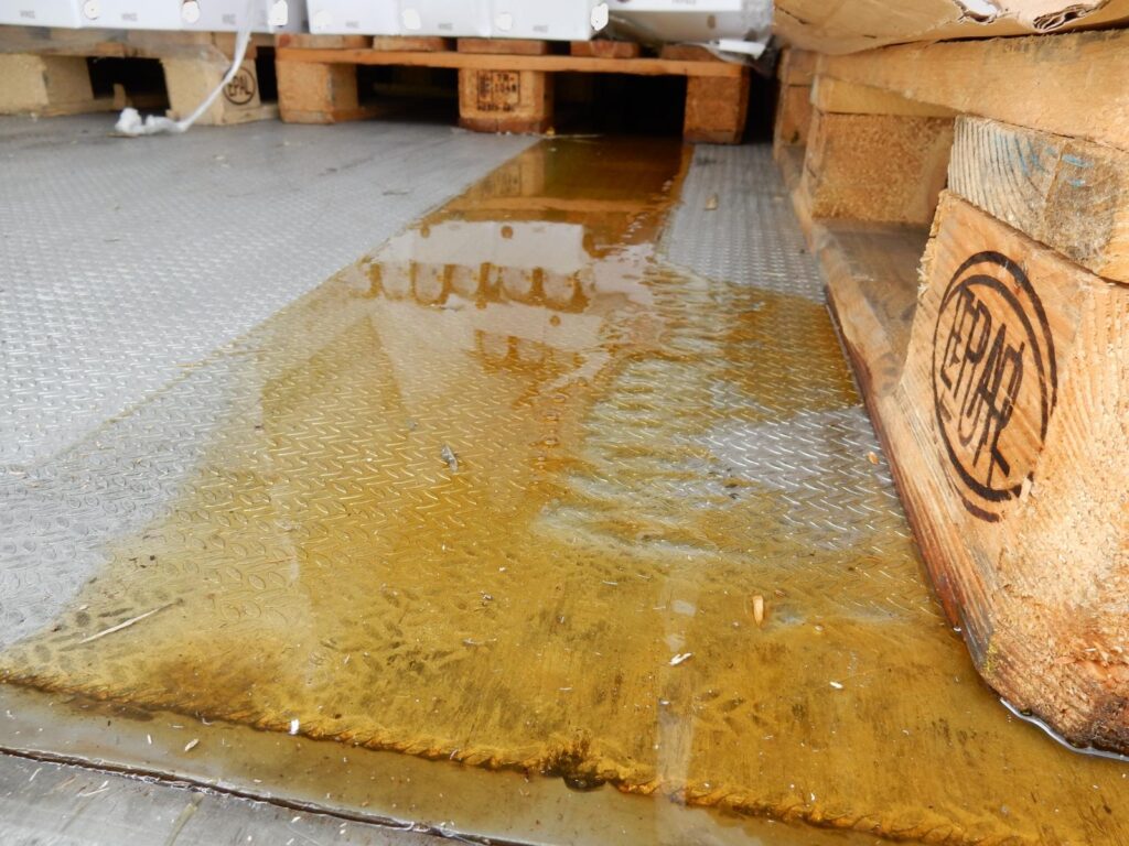 Nasse Holzpaletten mit fluessigkeitslache auf Metallboden auf LKW Ladefläche – EPAL-Stempel auf Palette sichtbar-transporttechniker-de