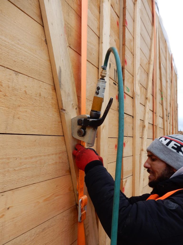 Arbeiter nagelt Holzkonstruktion mit Nagelpistole und Schlauch – transporttechniker.de