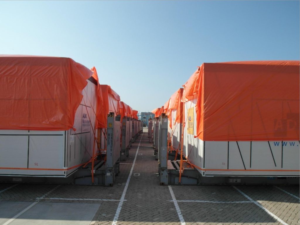 Reihe von Containern mit orangen Planen im Hafen – transporttechniker.de
