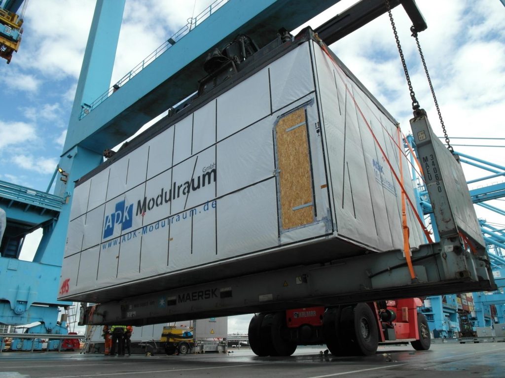 Foto eines ADK Modulraum GmbH Containers beim Schwerlastumschlag mit Kran im Hafen: www.ADK-Modulraum.de
