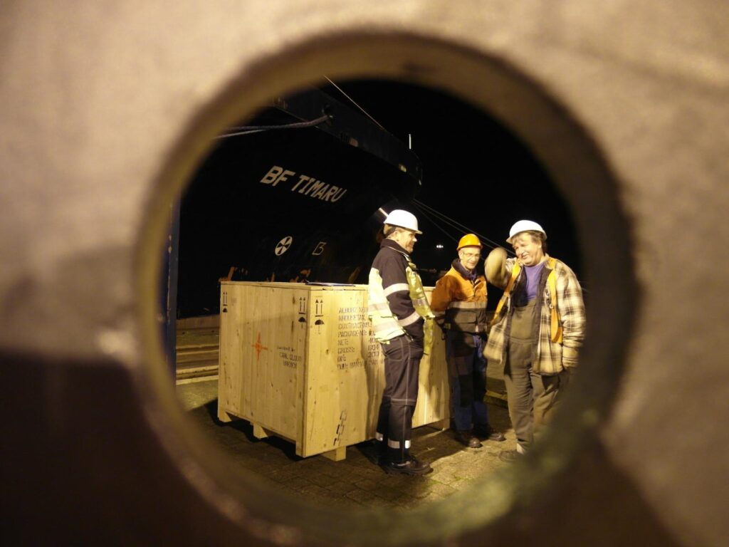 Foto eines Arbeiters in gelber und orange Sicherheitskleidung beim Schweißen mit Schweißmaske und sichtbaren Funken für Schwerlast-Metallarbeiten