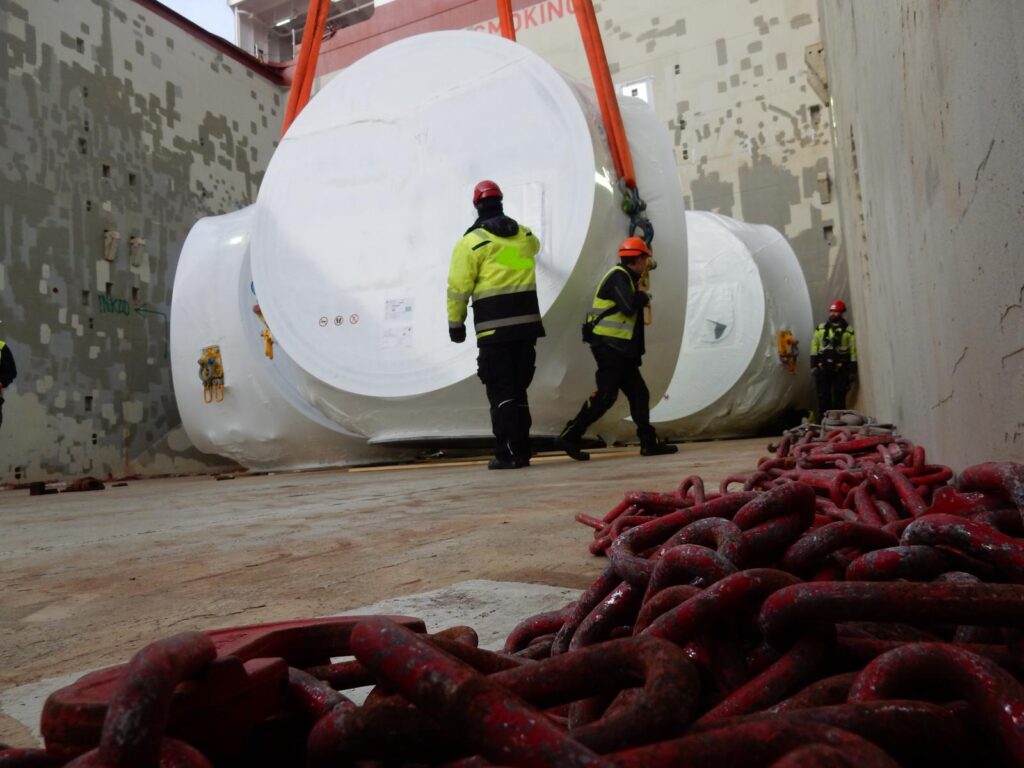 Hafenarbeiter setzen Schwerlast ins Lowerhold – transporttechniker.de