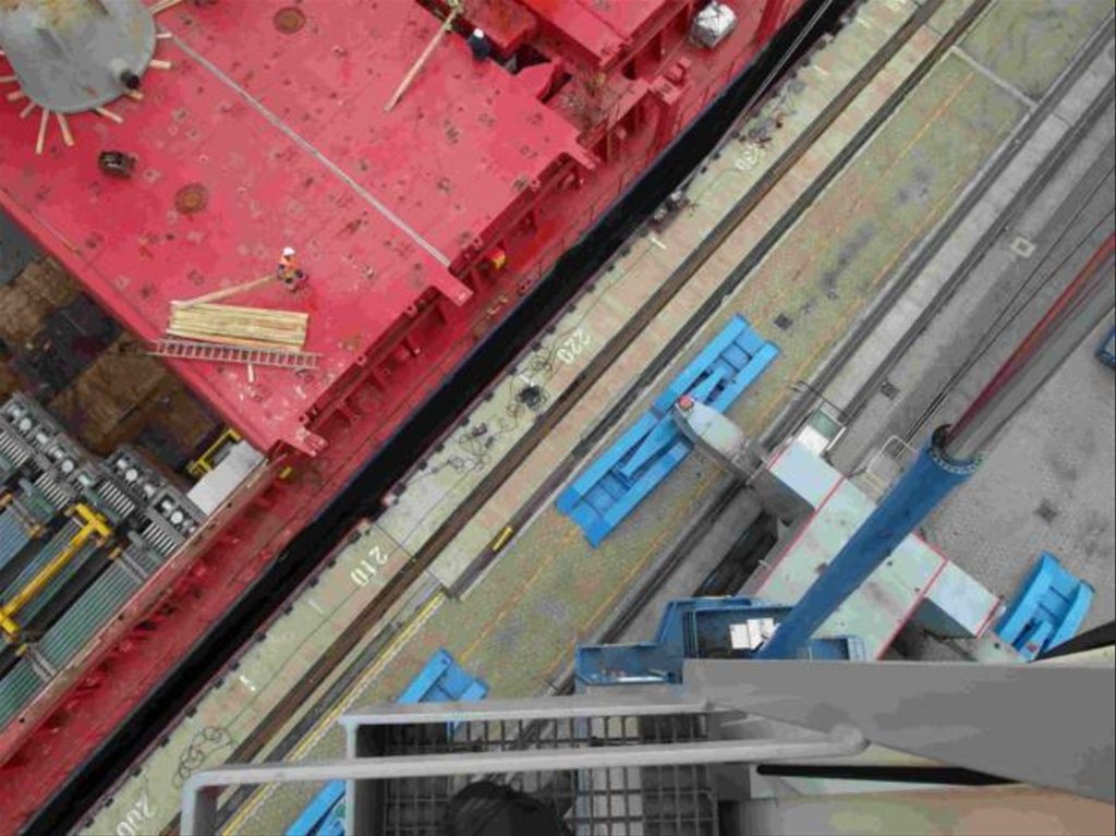 Kranausleger lädt Schiff im Hafen mit blauen Containern – transporttechniker.de