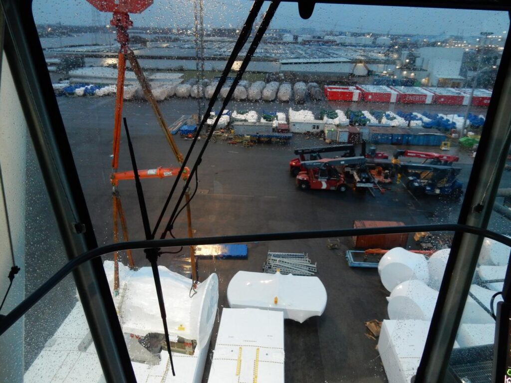 Blick aus Kranführerhaus auf Hafen mit Containern bei Regen – transporttechniker.de