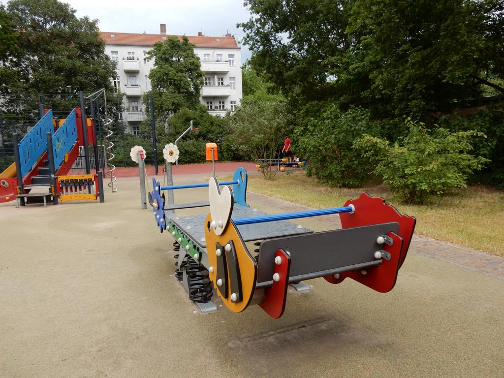 Spielplatz in Berlin mit bunter Wippe, Klettergerüsten und Fallschutzboden – transporttechniker.de
