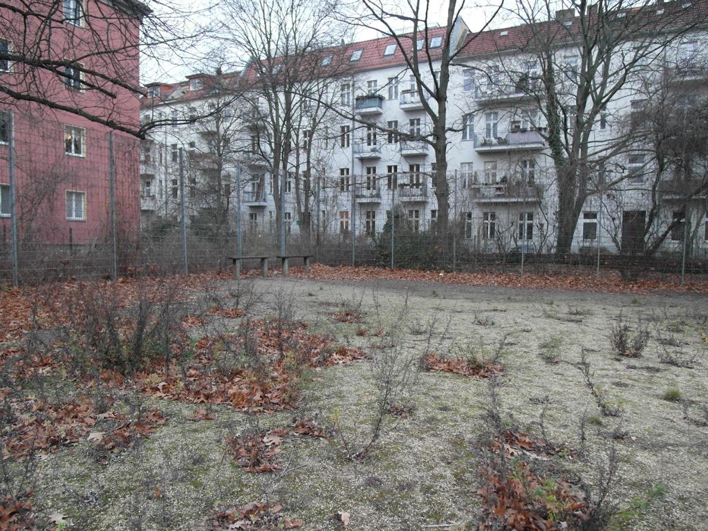 Spielplatz in der Dusekestraße, Berlin – Ist-Zustand im Herbst mit karger Vegetation, Sandfläche und umgebenden Wohnhäusern – transporttechniker.de
