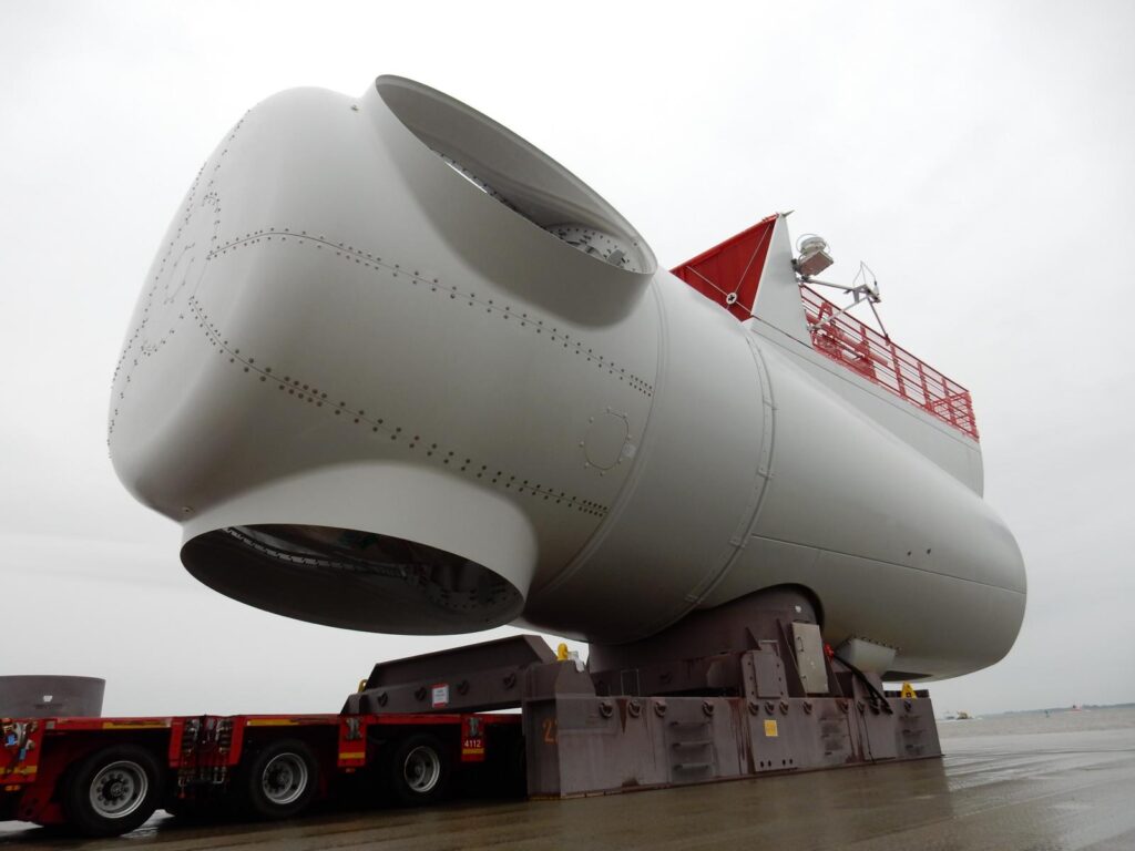 Windkraft-Turbinenhaus auf Schwerlasttransportfahrzeug mit roter Plattform und Geländer – transporttechniker.de